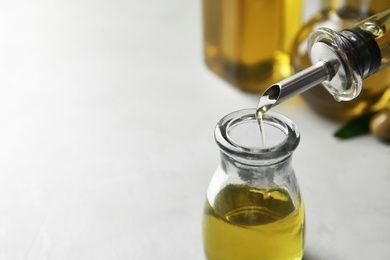 Pouring fresh olive oil into bottle on table