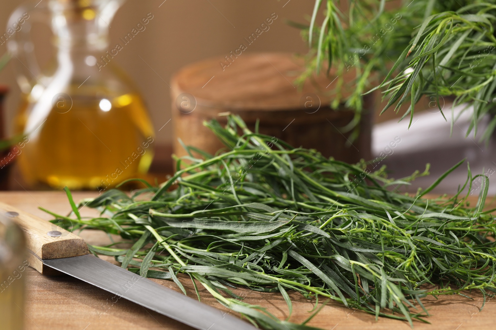 Photo of Fresh tarragon leaves and knife on wooden board, closeup