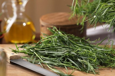 Fresh tarragon leaves and knife on wooden board, closeup