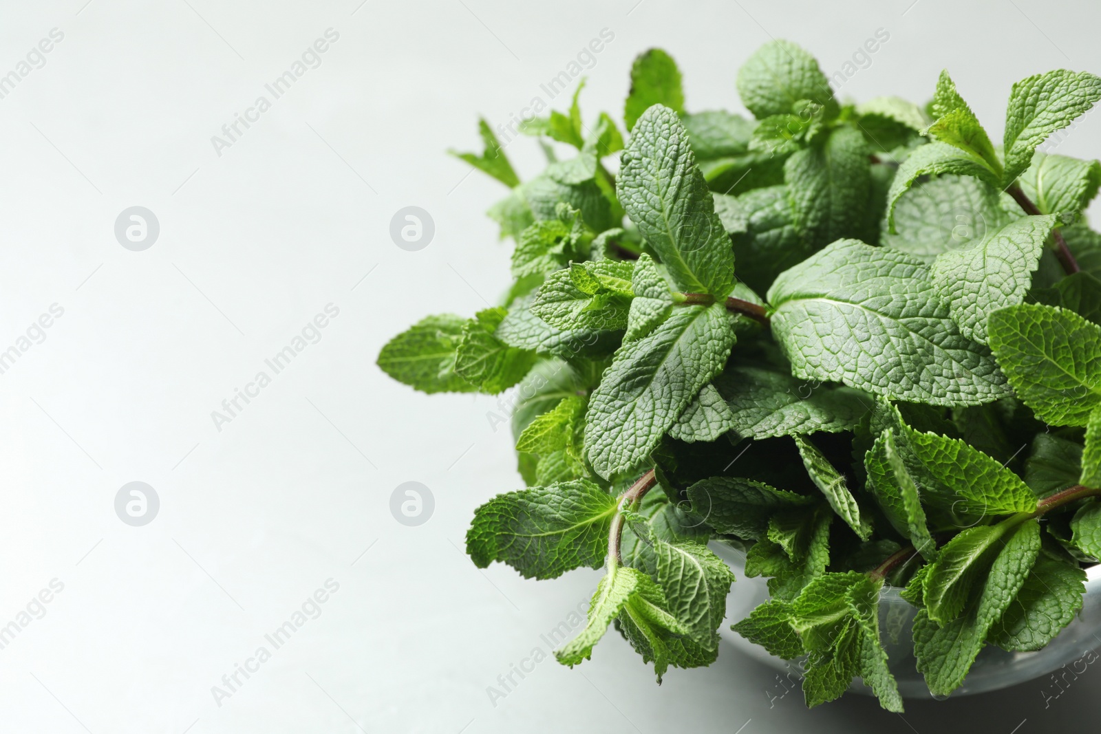 Photo of Bowl with fresh green mint on table. Space for text