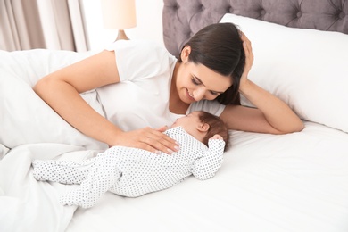 Photo of Happy woman with her cute baby on bed