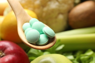 Photo of Dietary supplements. Spoon with pills over food products, closeup. Space for text