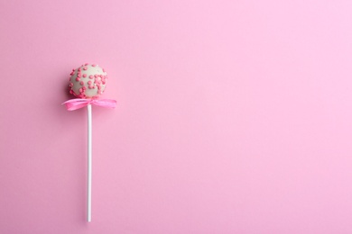 Tasty cake pop with bow on light pink background, top view. Space for text