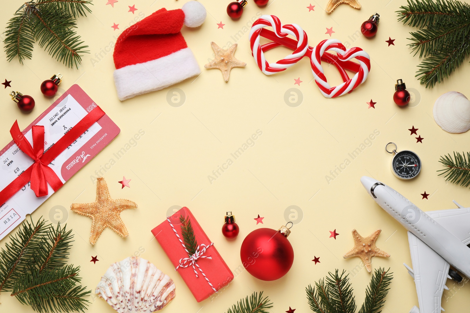 Photo of Frame with toy airplane, Santa hat, festive decor and space for text on yellow background, flat lay. Christmas vacation