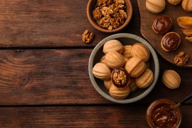 Photo of Delicious nut shaped cookies with boiled condensed milk on wooden table, flat lay. Space for text
