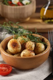 Photo of Delicious grilled potatoes with tarragon in bowl on table