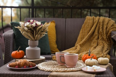 Photo of Rest on terrace with rattan furniture. Drink, dessert and autumn decor on table