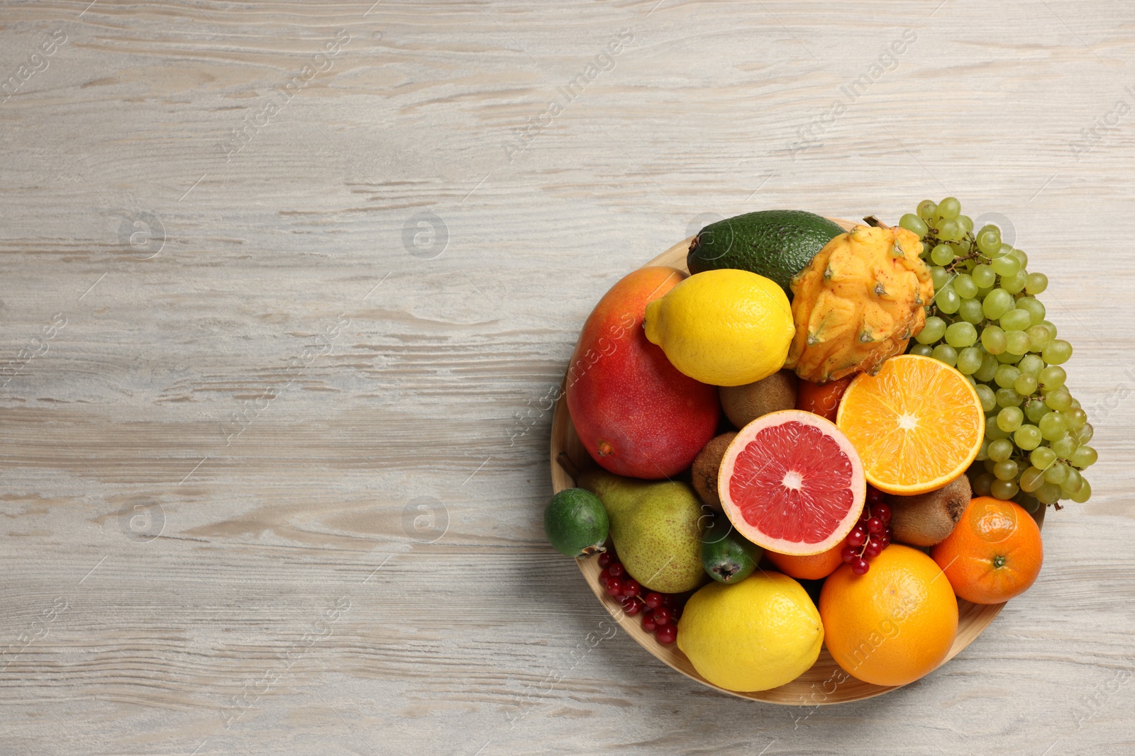 Photo of Different ripe fruits and berries on light wooden table, top view. Space for text