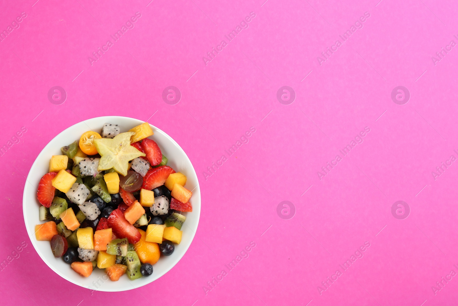 Photo of Delicious exotic fruit salad on pink background, top view. Space for text