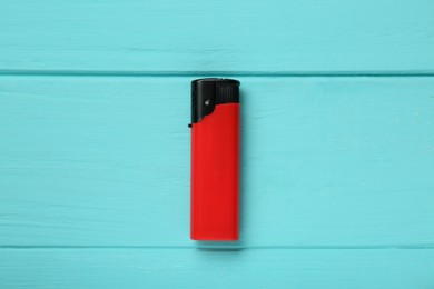 Stylish small pocket lighter on turquoise wooden background, top view