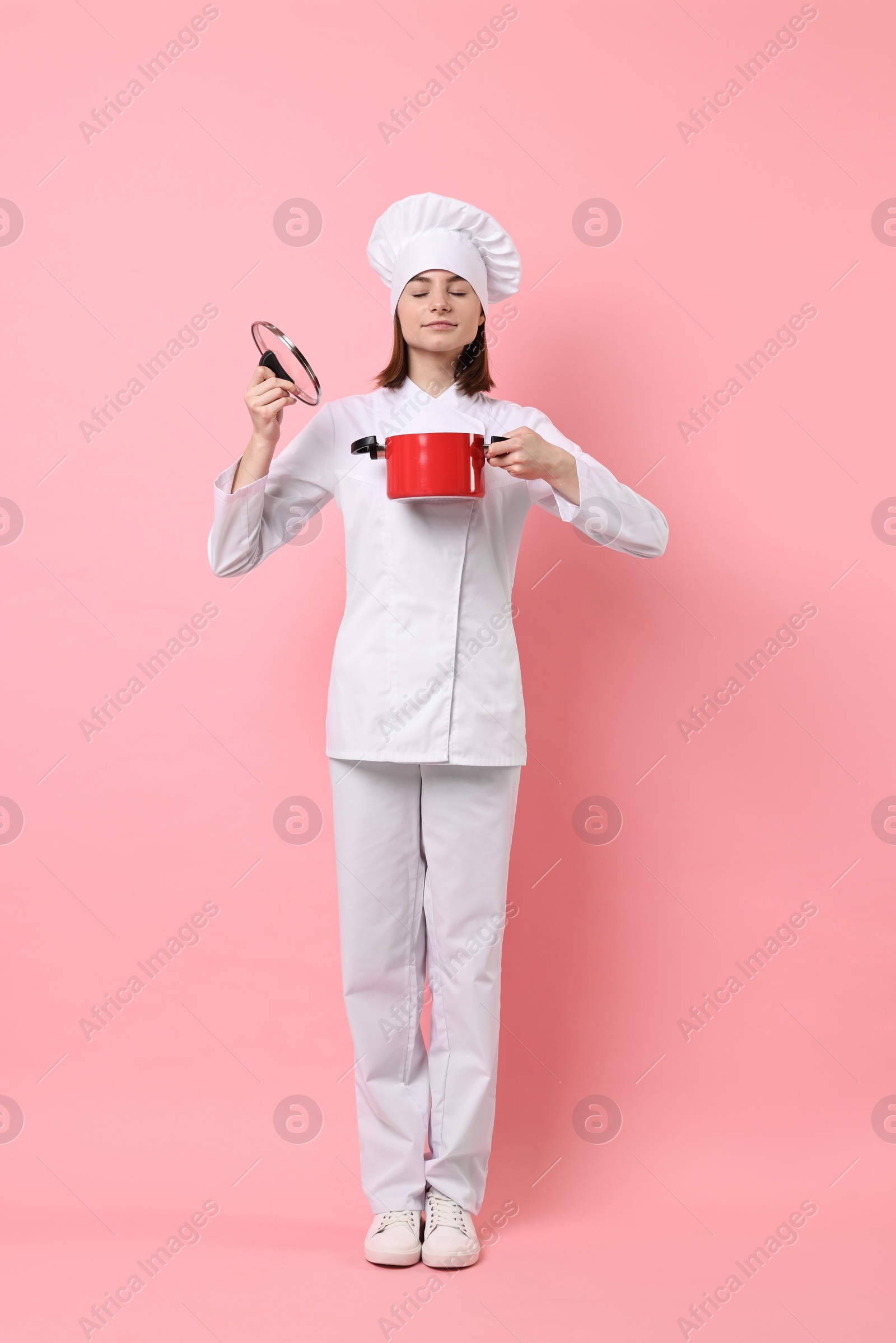 Photo of Professional chef with cooking pot on pink background