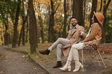 Romantic young couple spending time together in autumn park, space for text