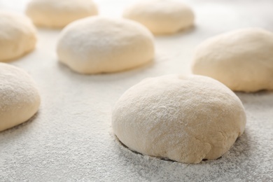 Photo of Fresh raw dough with flour on table