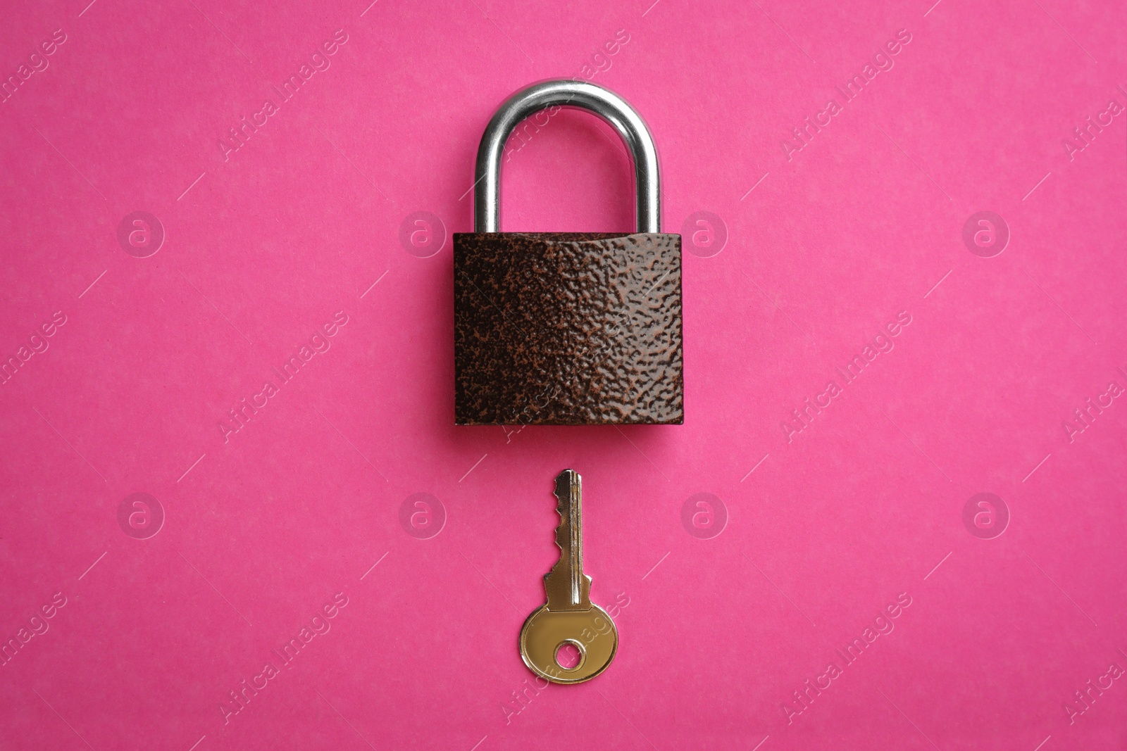 Photo of Modern padlock with key on pink background, flat lay