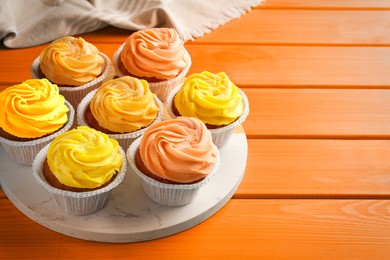 Tasty cupcakes on orange wooden table, space for text