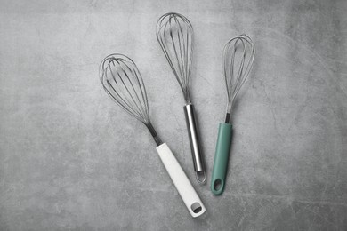 Metal whisks on gray table, top view