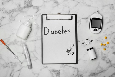 Flat lay composition with word "Diabetes", digital glucometer and medicine on marble background