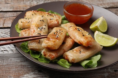 Photo of Tasty fried spring rolls served on wooden table, closeup