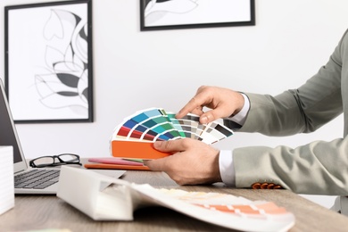 Photo of Male designer working with color palette at office table, closeup