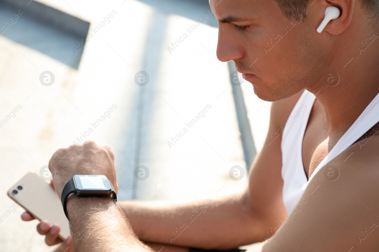 Photo of Man checking fitness tracker after training outdoors, closeup