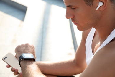 Photo of Man checking fitness tracker after training outdoors, closeup