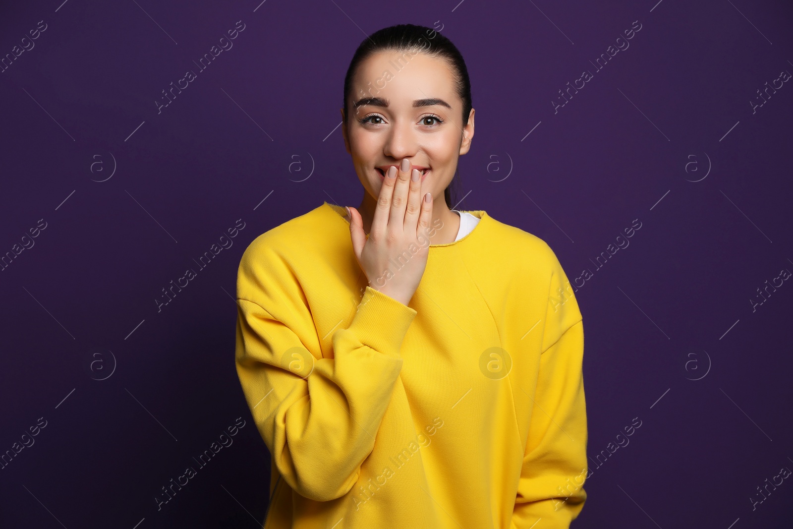 Photo of Beautiful young woman laughing on purple background. Funny joke