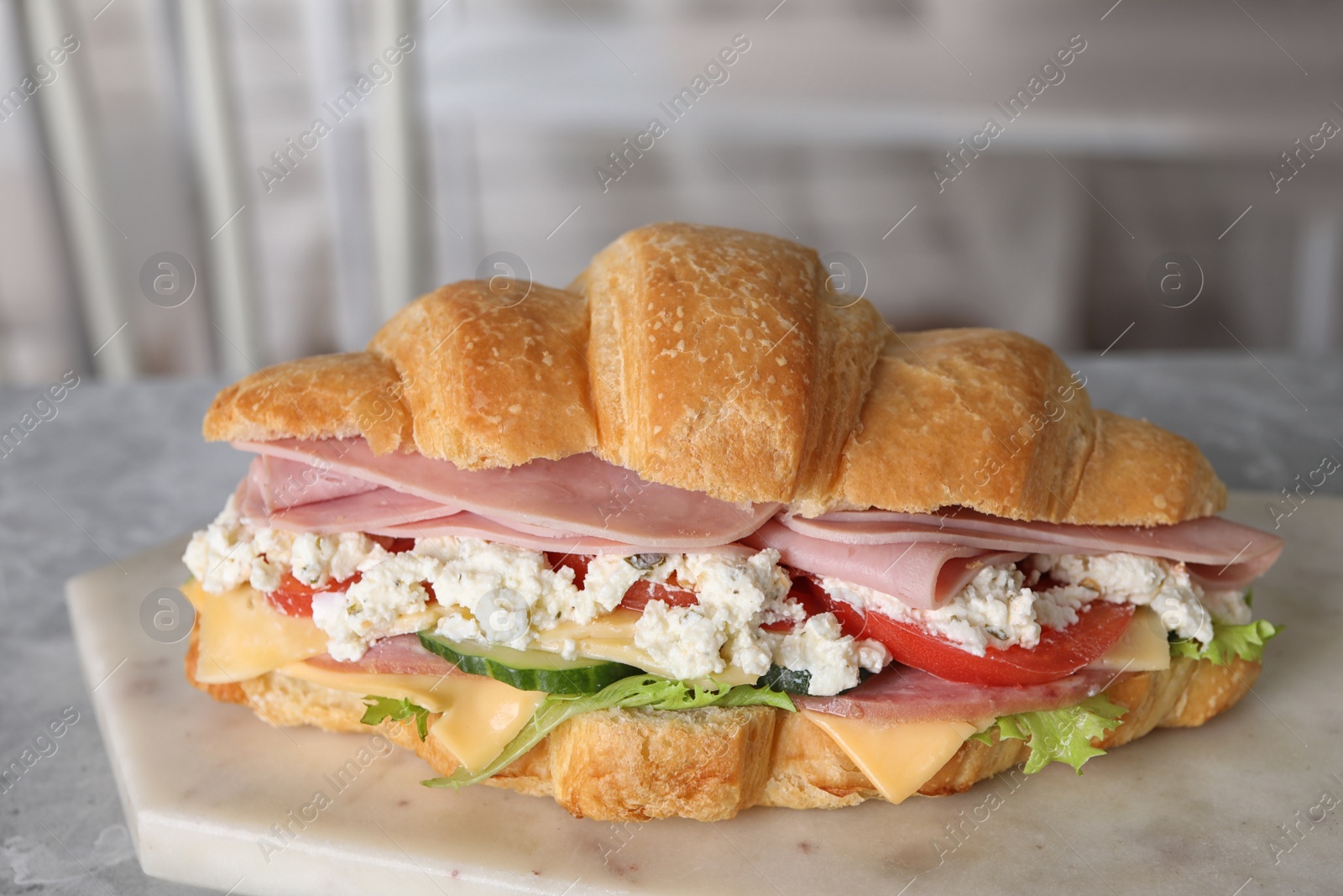 Photo of Tasty croissant sandwich with ham on table indoors, closeup