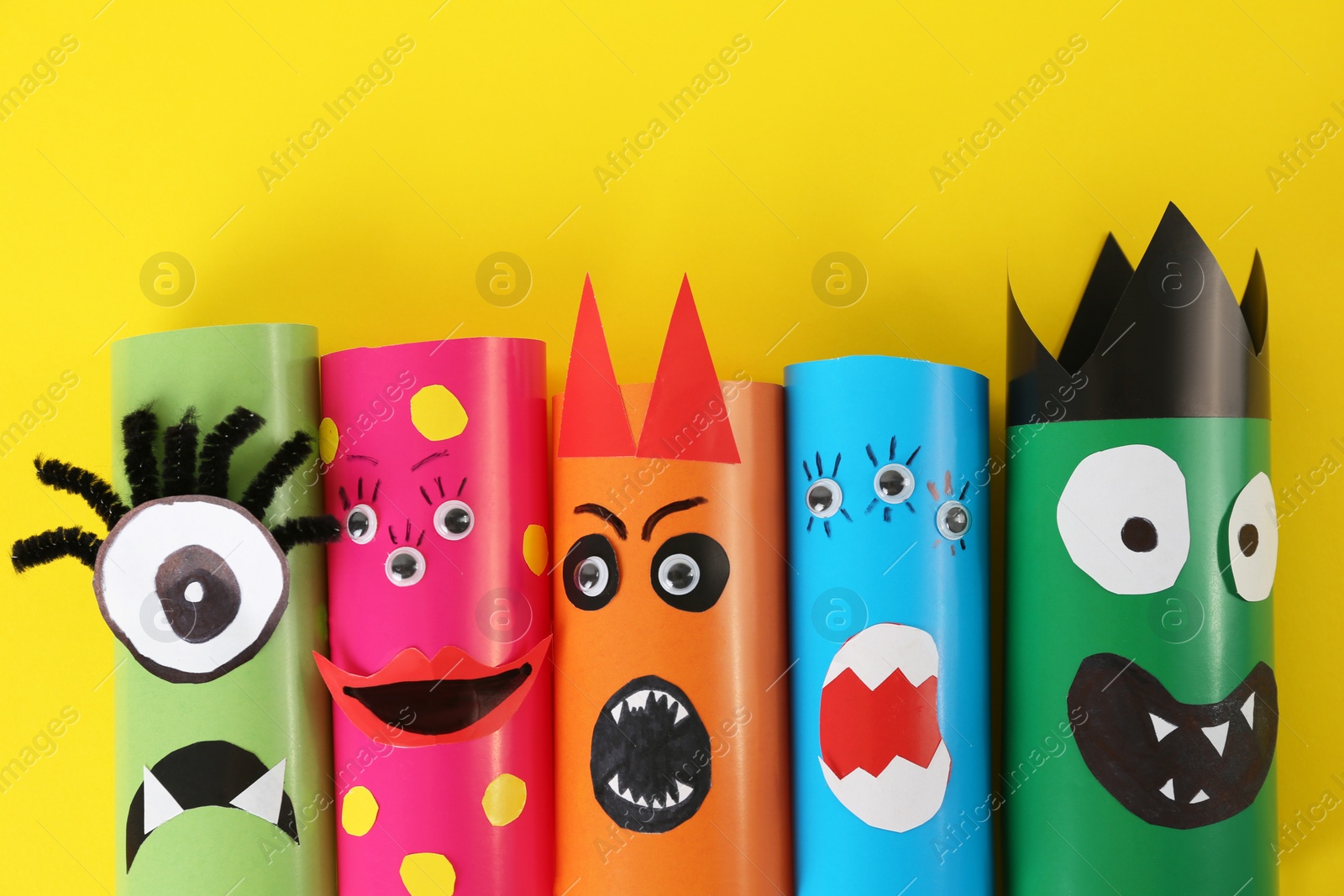 Photo of Funny monsters on yellow background, flat lay. Halloween decoration