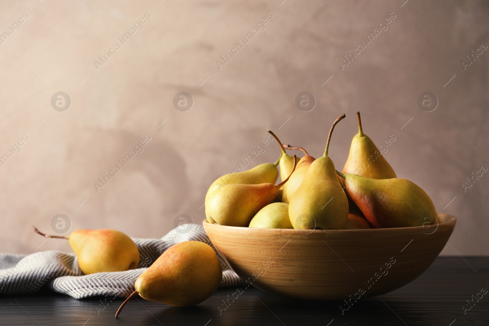 Photo of Bowl with ripe pears on table against grey background. Space for text