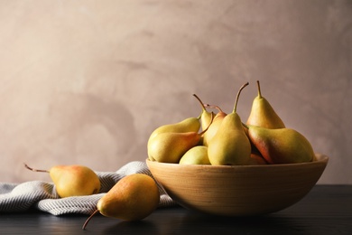 Photo of Bowl with ripe pears on table against grey background. Space for text