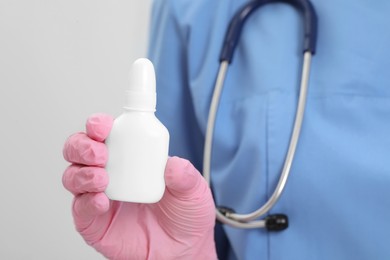 Photo of Doctor holding nasal spray on white background, closeup