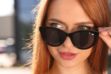 Photo of Beautiful woman in sunglasses outdoors, closeup. Space for text