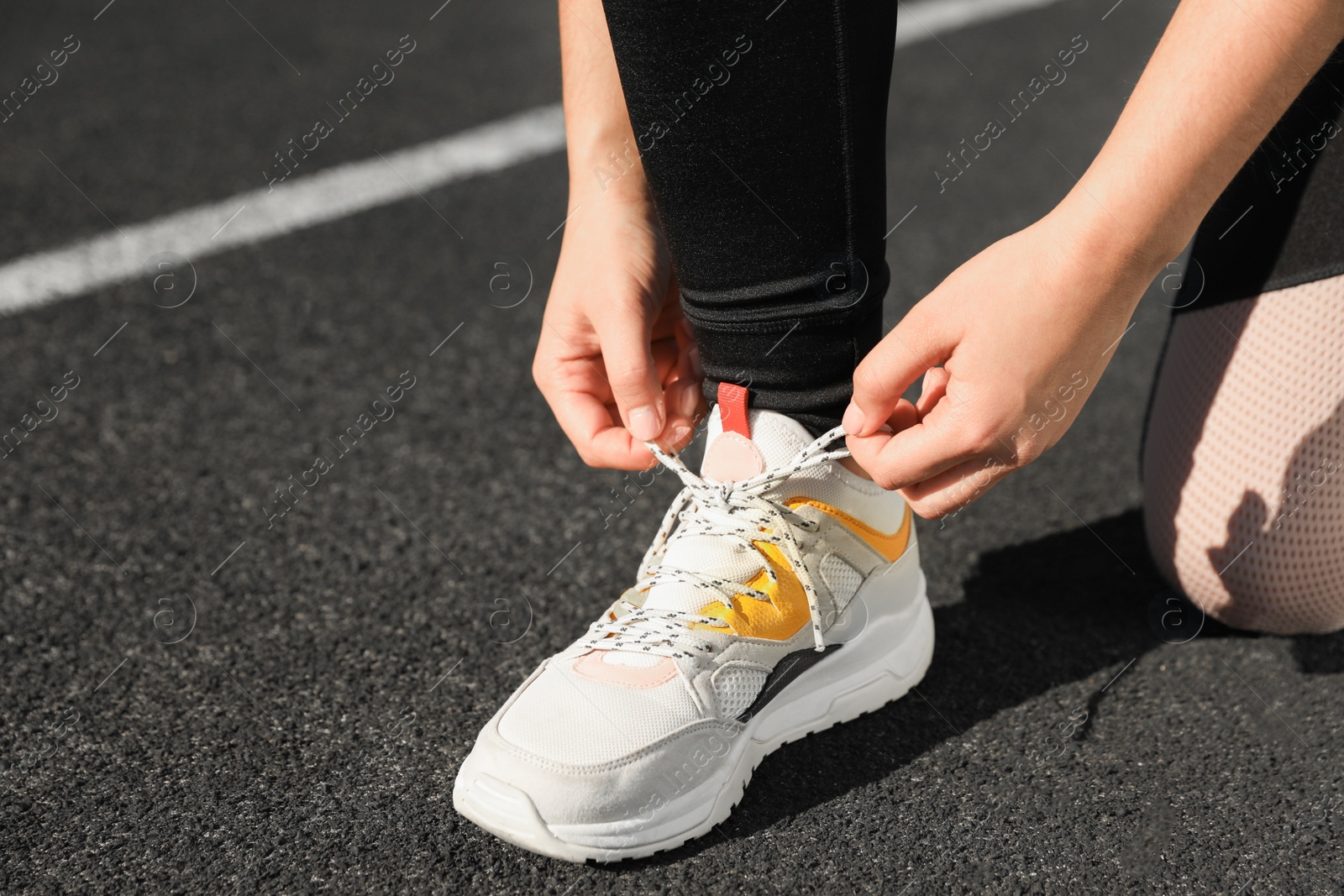 Photo of Young woman tying shoelaces at stadium on sunny day