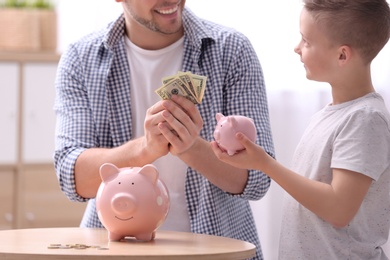 Photo of Family with piggy banks and money at home