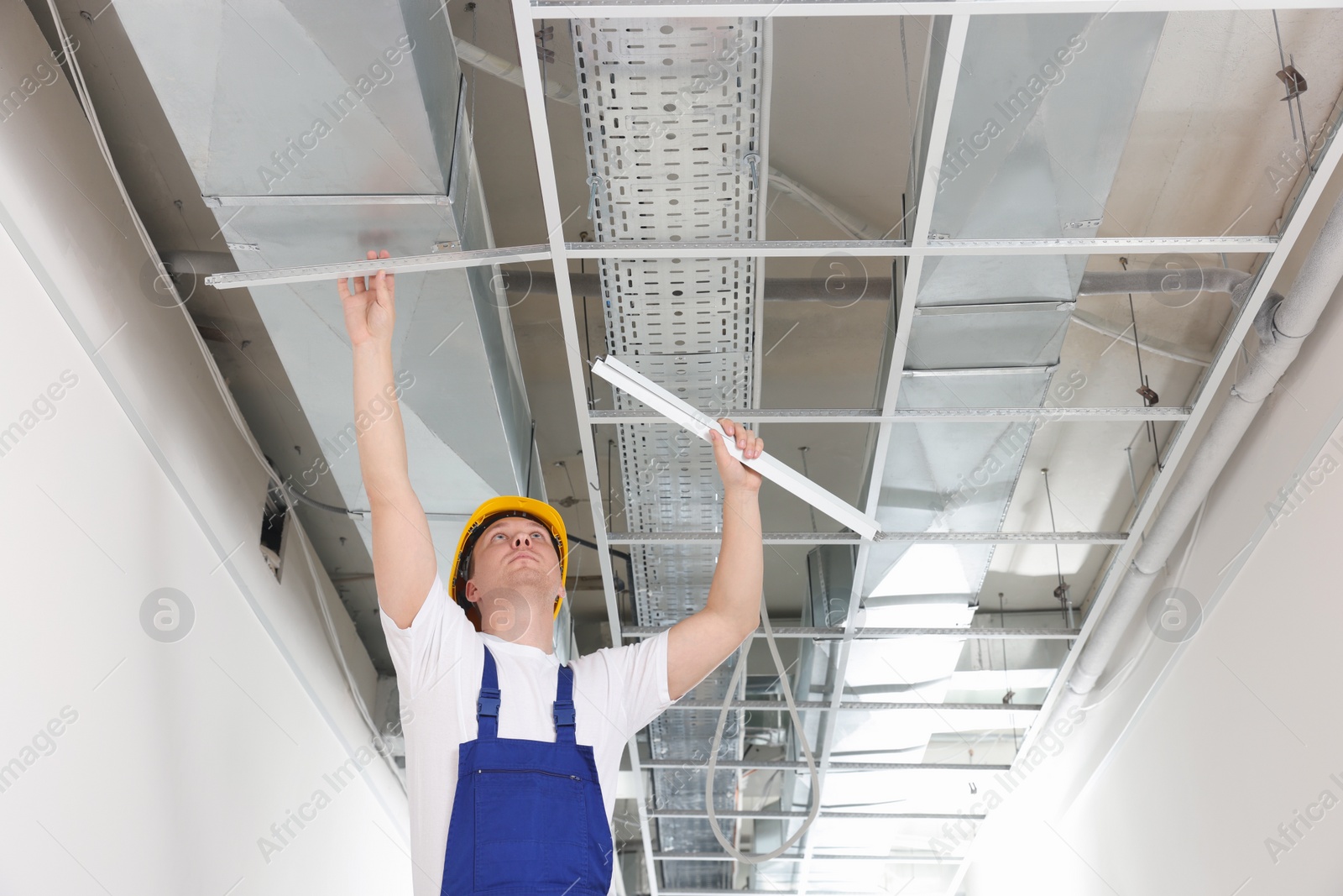 Photo of Worker installing metal frame indoors. Suspended ceiling