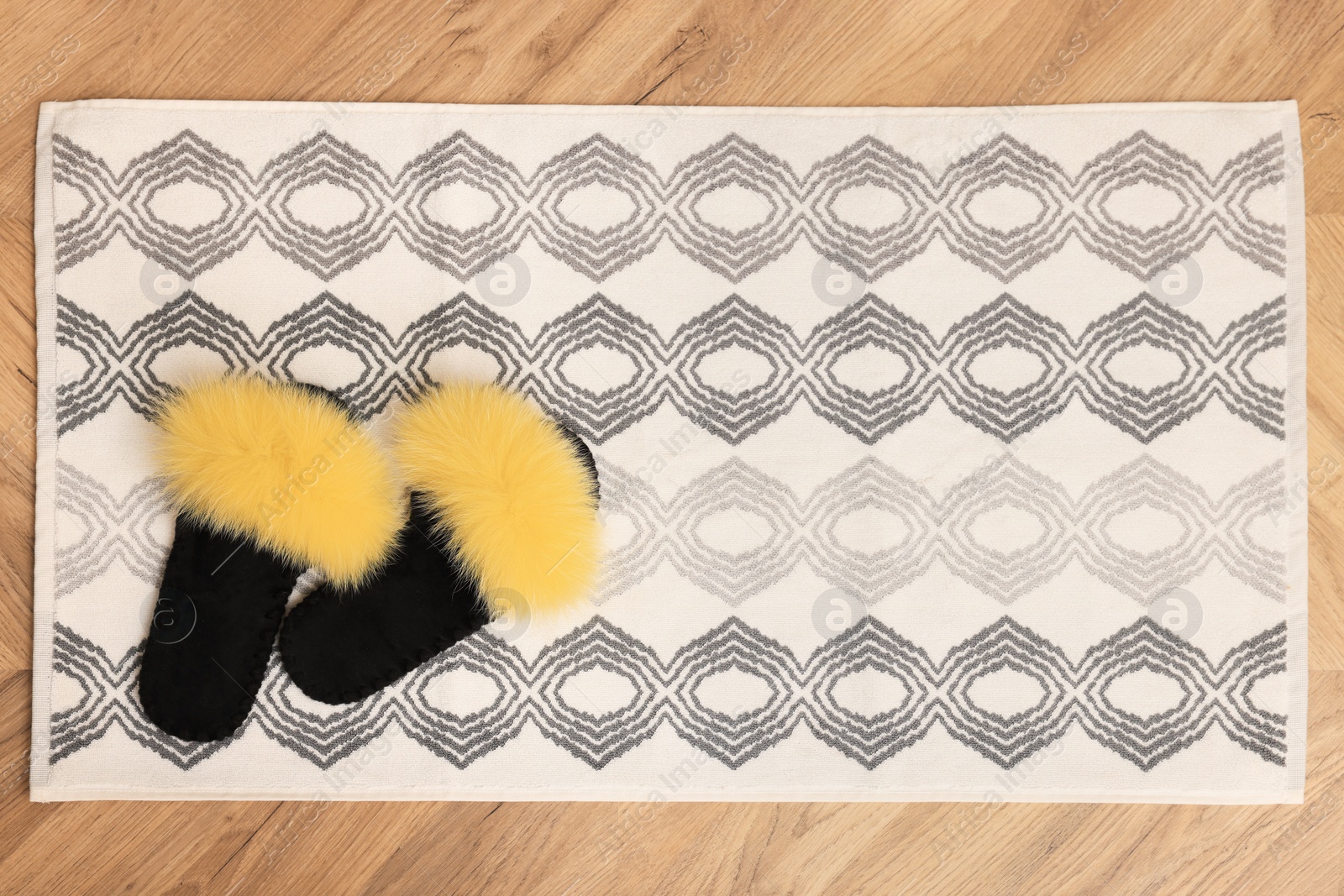 Photo of Soft bath mat and slippers on floor, top view