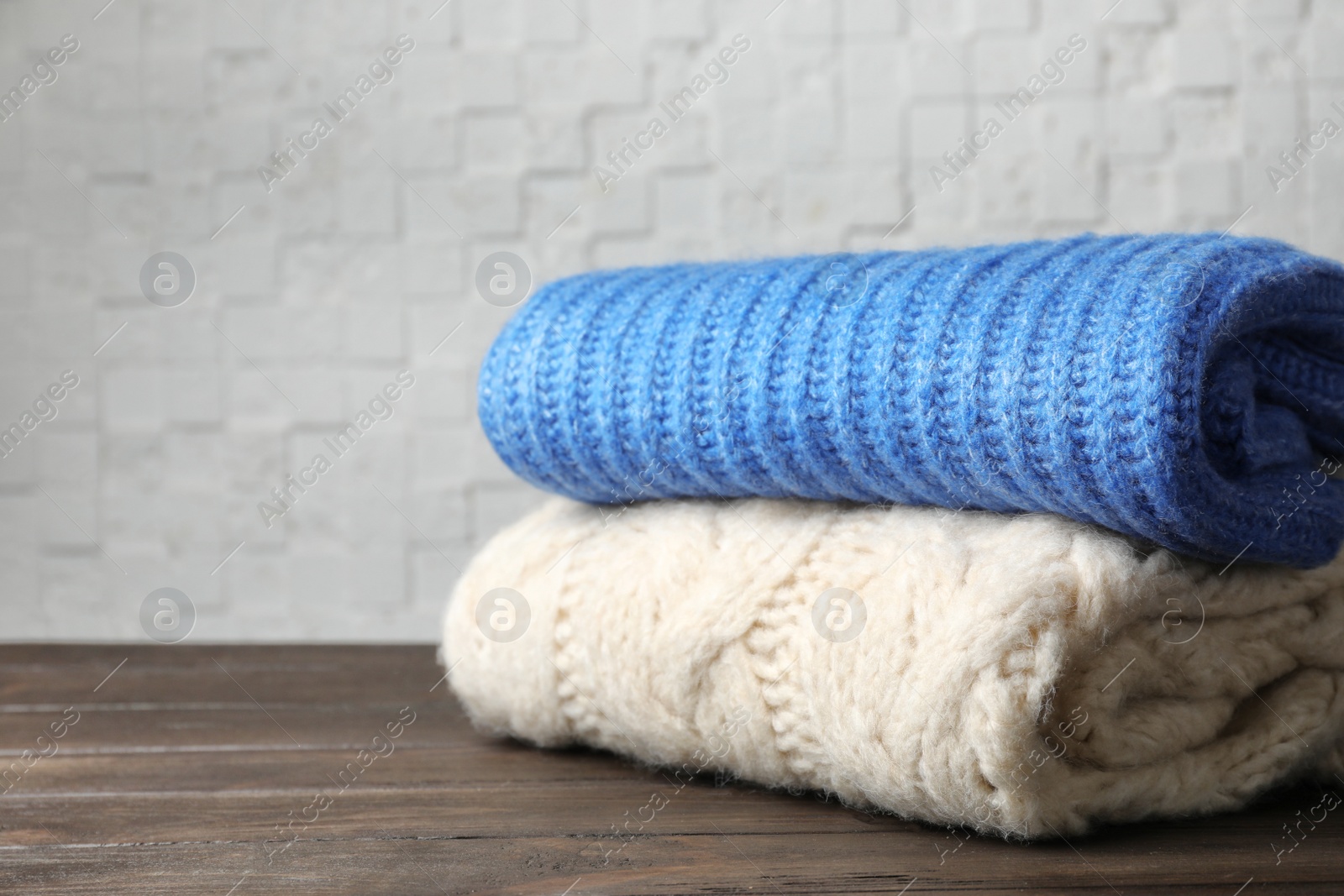 Photo of Stack of folded knitted sweaters on table. Space for text