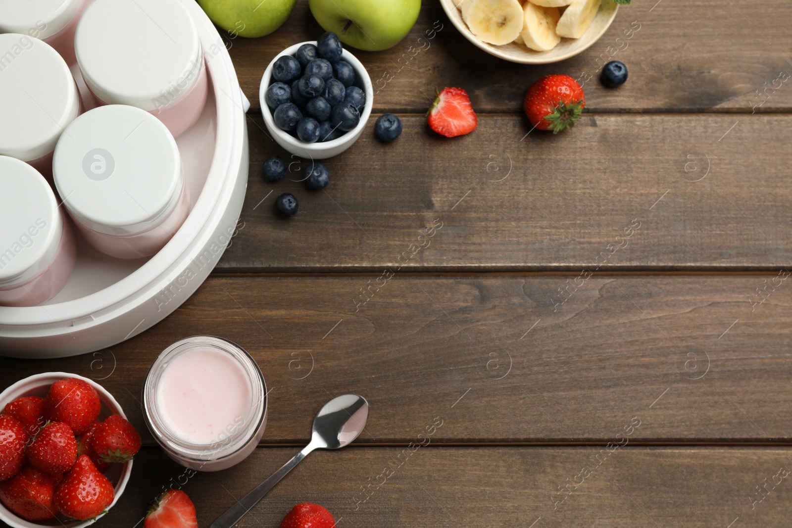 Photo of Modern yogurt maker with full jars and different fruits on wooden table, flat lay. Space for text