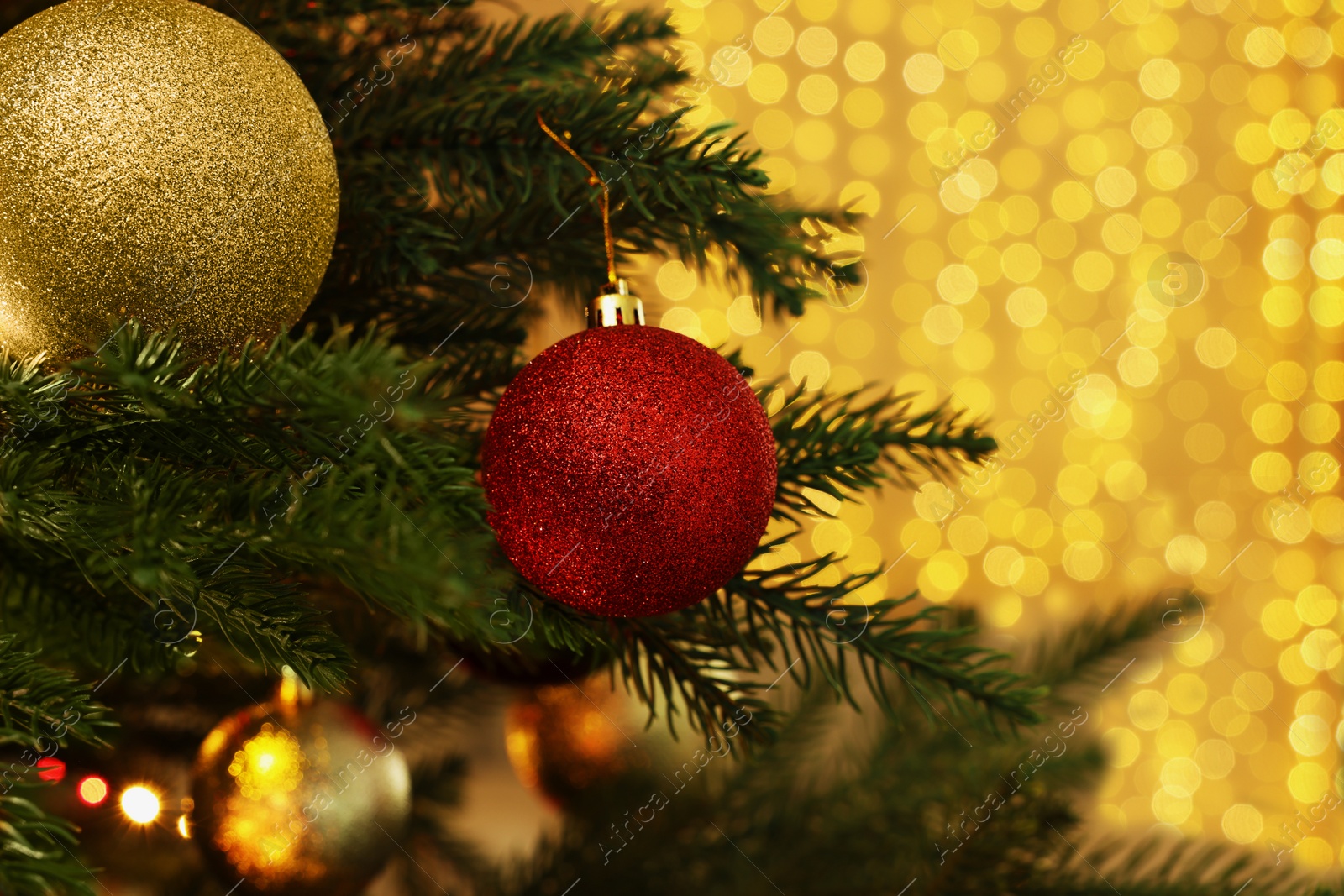 Photo of Closeup of shiny baubles hanging on Christmas tree indoors