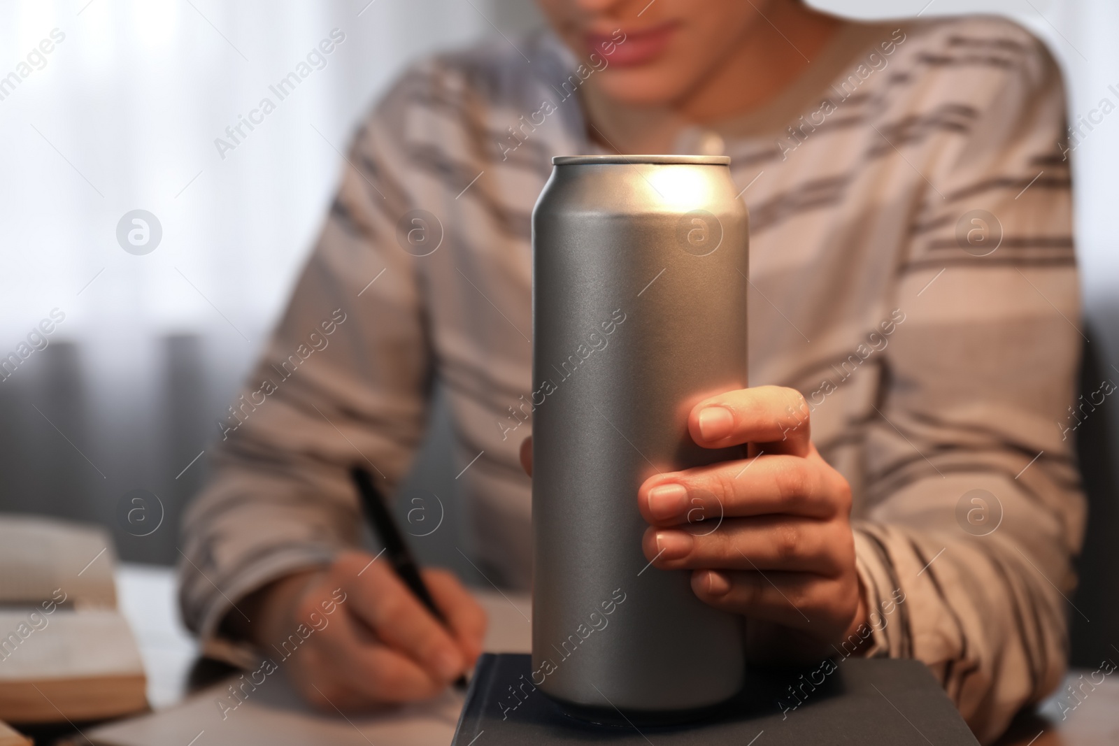 Photo of Tired young woman with energy drink studying at home, closeup