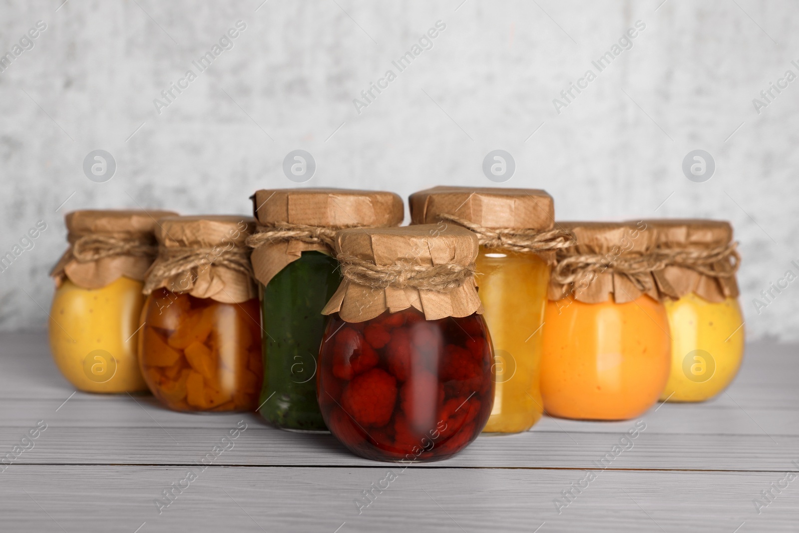Photo of Jars with canned fruit jams on wooden table