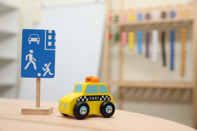 Photo of Miniature road sign and car on wooden table, space for text. Montessori toy