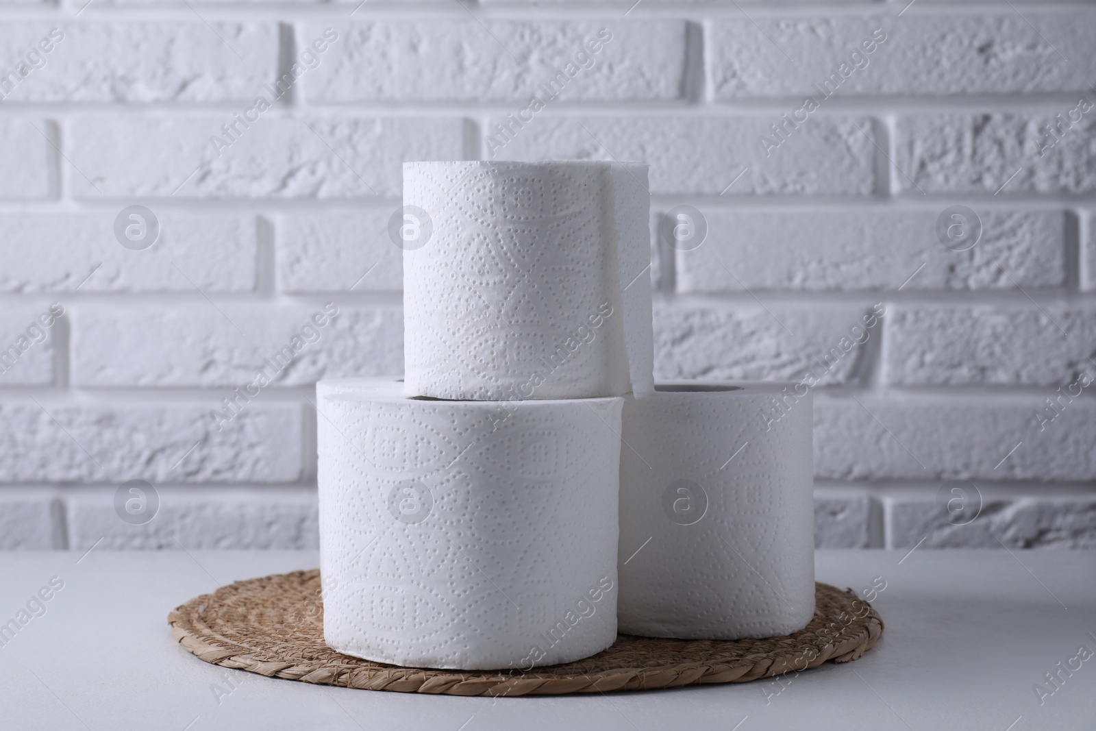 Photo of Toilet paper rolls on white table against brick wall