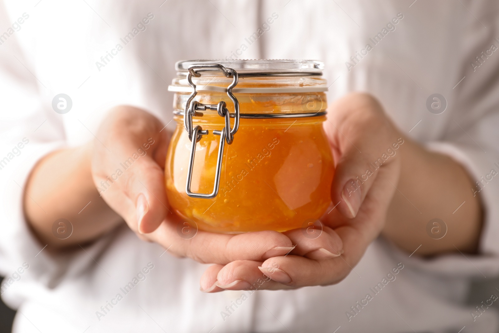 Photo of Woman with jar of orange jam, closeup