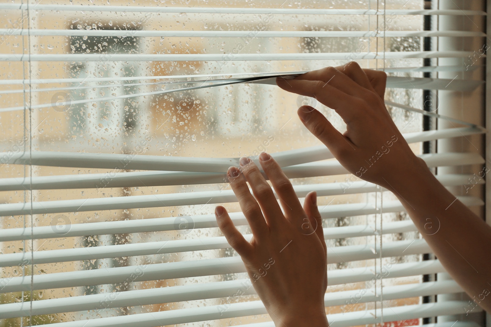 Photo of Woman opening window blinds, closeup. Space for text