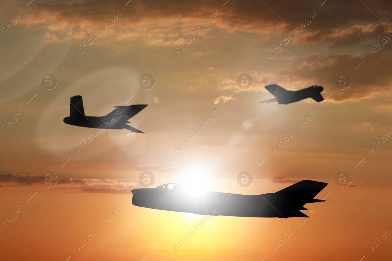 Image of Silhouette of jet fighter in cloudy sky at sunset