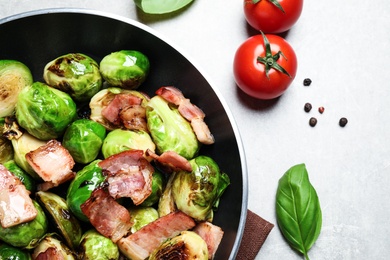 Photo of Delicious Brussels sprouts with bacon in pan on light table, closeup