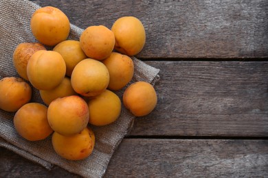 Delicious ripe apricots with napkin on wooden table, top view. Space for text