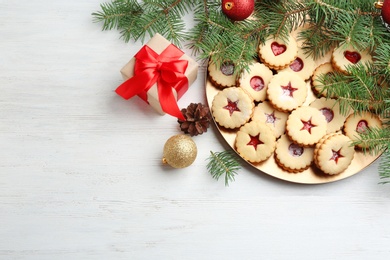 Christmas decorations and delicious Linzer cookies with sweet jam on wooden background, top view