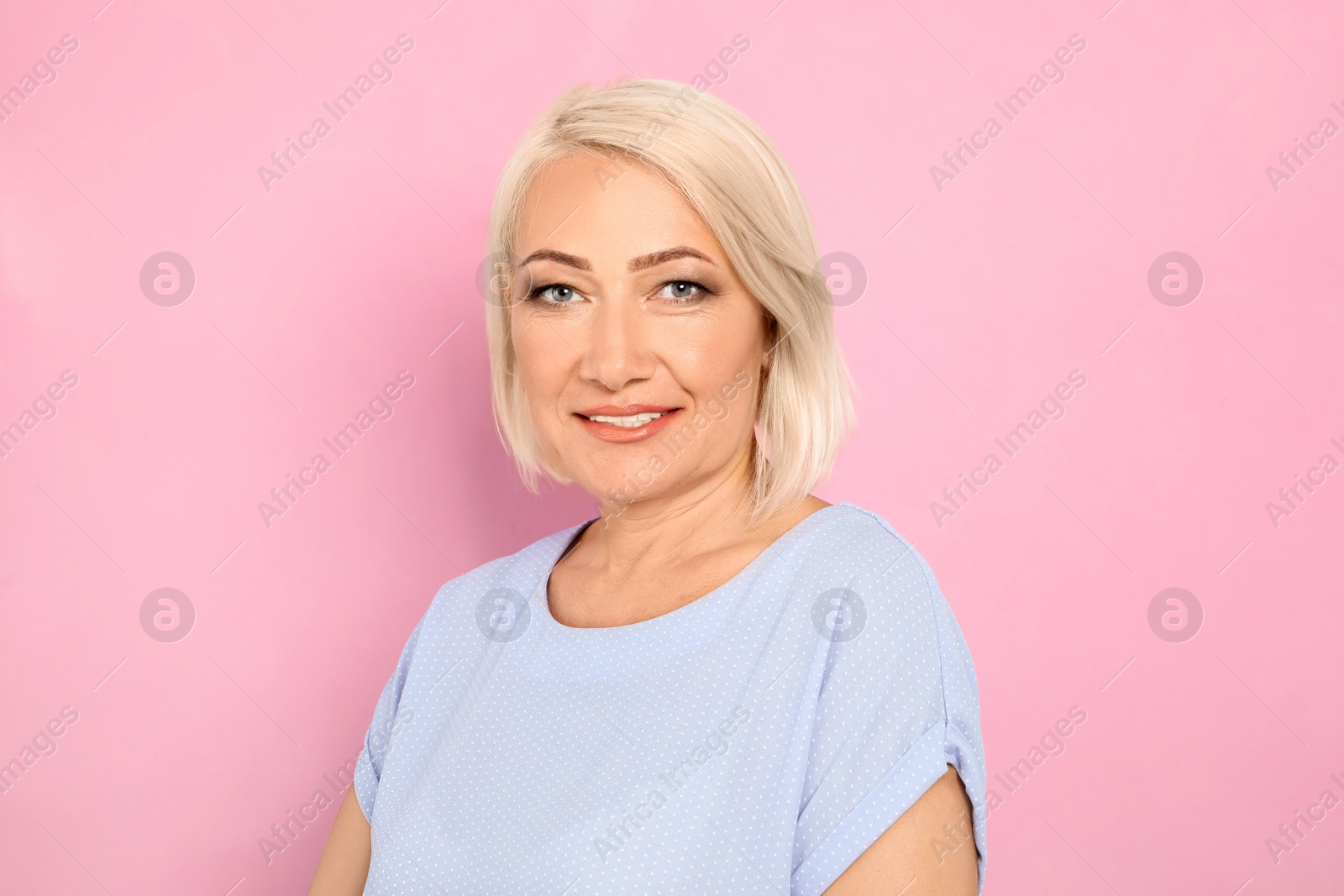 Photo of Portrait of mature woman with beautiful face on pink background